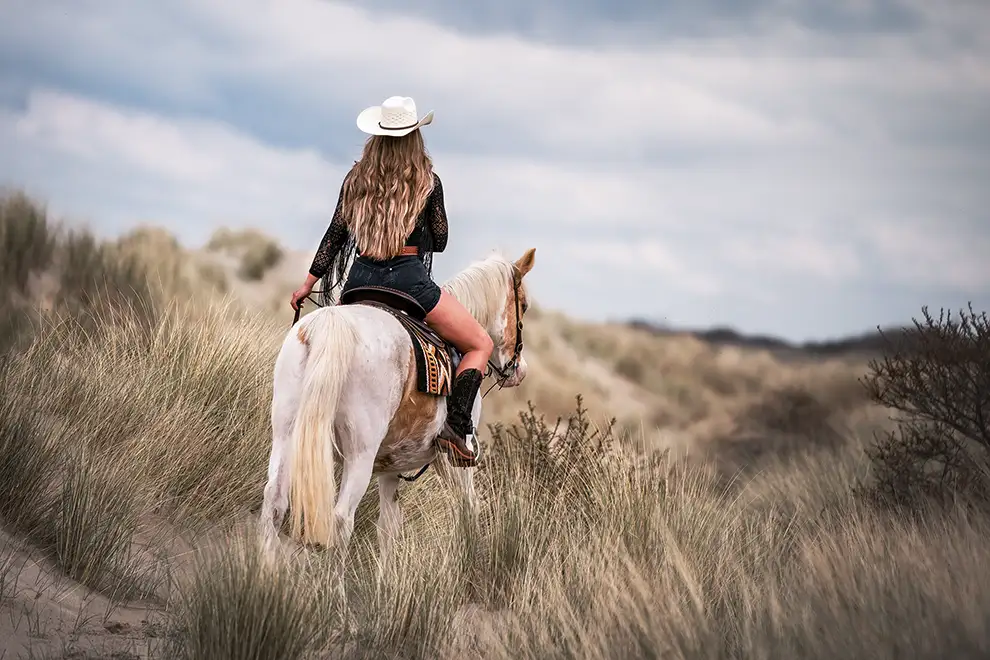 Frau reitet auf einem Pferd in den Dünen von Renesse